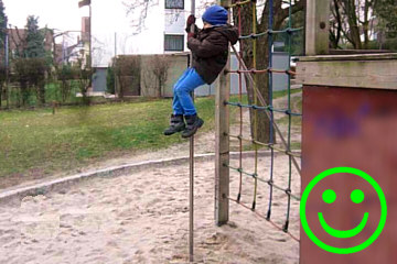 ein 4-jähriger Junge rutscht auf dem Spielplatz die Rutschstange herunter