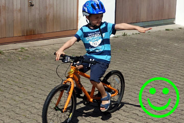 ein 5-Jähriger Junge fährt einhändig Fahrrad